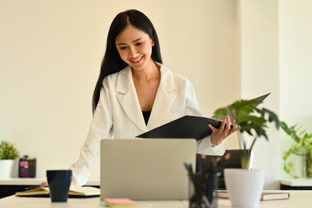 Confident female analyst in stylish suit watching online webinar on laptop screen. Business, communicating and technology.の写真素材