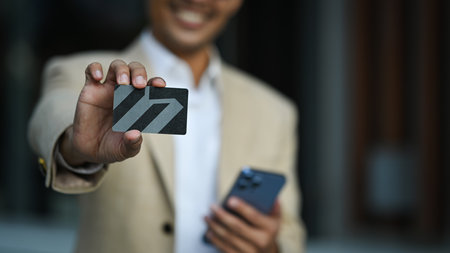 Select focus on hand. Smiling businessman holding credit card. Electronic money, contactless payment concept.の写真素材
