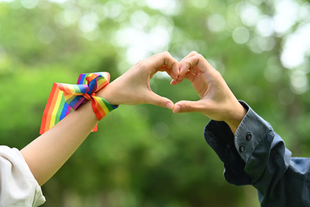 Lesbian couple making heart with their hands on blurred nature background. Support marriage equality for LGBT people.の写真素材