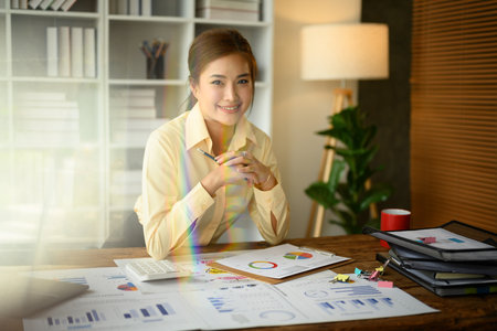 Image of professional female analyst sitting in modern office and smiling at camera.の写真素材