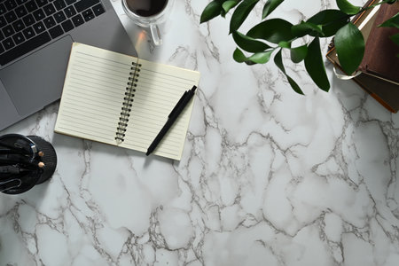 Blank spiral notepad, laptop and coffee cup on marble table. Top view with copy space.の写真素材