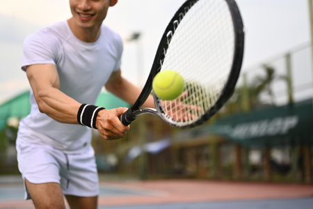 Shot of male athlete hitting ball with racket on outdoor court. Fitness, sport, exercise concept.