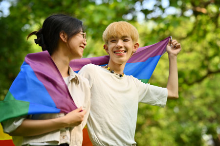 Image of young people with LGBTQ pride flag standing outdoor, supporting LGBTQ community and equality social. High quality photoの写真素材