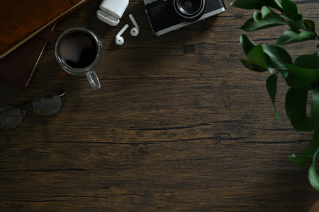 Flat lay, top view of retro camera, coffee cup, notepad and glasses on wooden table.の写真素材
