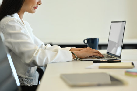 Side view of female office worker hands typing on laptop, checking marketing research results or statistics data at desk.の写真素材