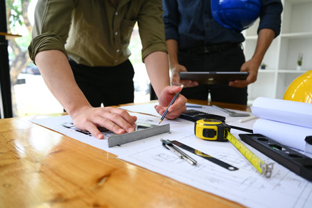 Team of engineers standing at meeting table, discussing construction process together.