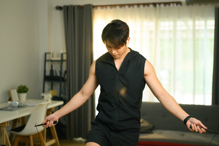 Sporty man exercising with skipping rope, doing domestic training at home. Fitness, sport and...
