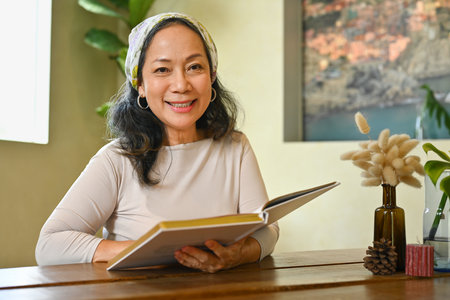 Image of happy beautiful middle age woman reading favorite novel, resting on weekend at home.