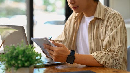 Cropped shot of young start up businessman writing notes in personal daily planner, planning workday...