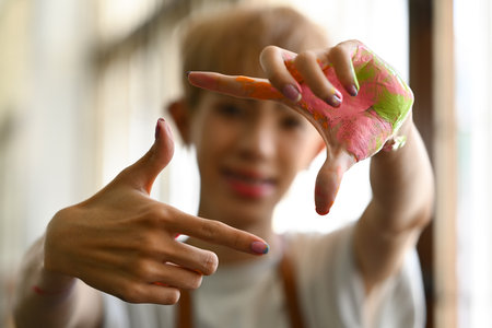 Select focus on hands. Young creative artist making a frame with his hands soiled with watercolor...