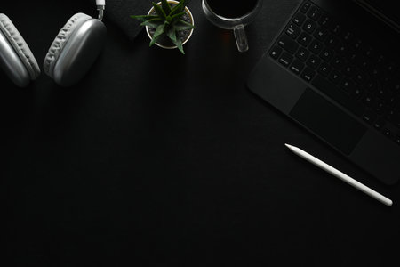 Dark modern workplace with laptop, coffee cup and wireless headphone on black leather. Top view with copy space.の写真素材