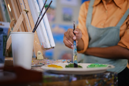 Closeup view of female artist mixing color oil painting on palette. Art, hobby and leisure activity concept.の写真素材