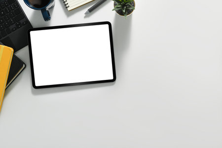 White office desk with digital tablet, coffee cup, laptop and notepad. Flat lay, top view with copy space.の写真素材