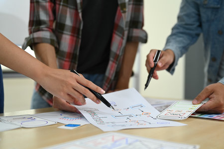 Cropped shot of designer team working on new website wireframe, planning application development for web mobile phone at meeting.の写真素材
