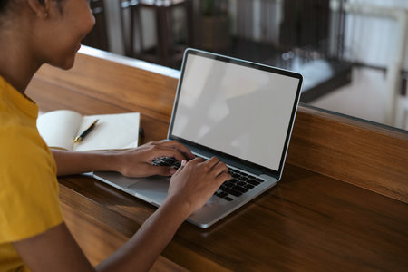 Side view of university student woman typing on laptop, doing homework, working on research project online.の写真素材