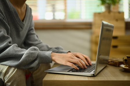 Cropped shot of young woman hands typing on laptop, communicating online, working remote from home.の写真素材