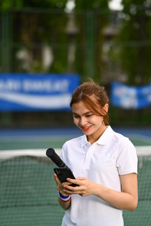 Smiling young woman taking rest after training and using mobile phone. Sport, training and active life concept.の写真素材