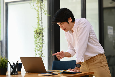 Handsome male manager looking at computer screen chatting online, communicating by conference video call.の写真素材
