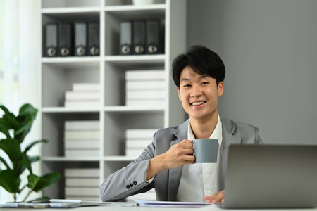 Successful young startup business entrepreneur sitting in office and smiling to camera.の写真素材