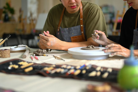 Man modeling clay in pottery workshop, creative activity, handicraft and hobbies concept.