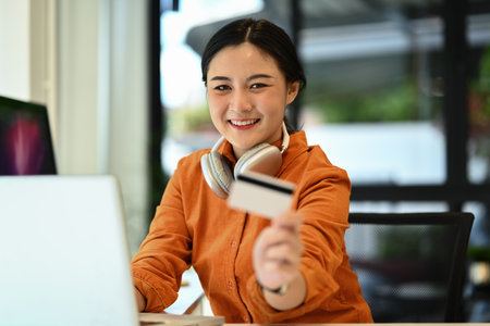 Cheerful young woman holding credit card laptop. E-commerce, banking service and shopping online.の写真素材
