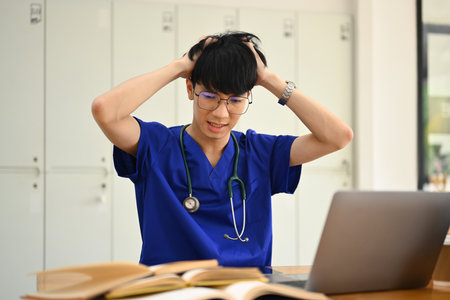 Frustrated male medical student having serious computer problem or feeling tired of studying for college exam.の写真素材
