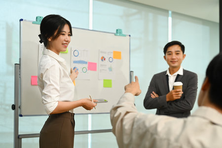 Smiling Asian female manager explaining information, talking about company strategy and business plan during meeting.の写真素材
