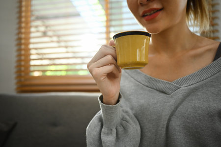 Happy woman drinking hot coffee, enjoying quality time with drinks in home.の写真素材