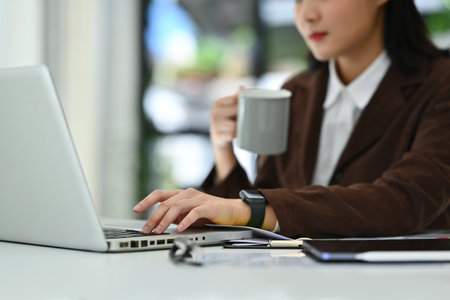 Select focused on hand of young businesswoman typing on laptop keyboard. Technology, business and communication.の写真素材