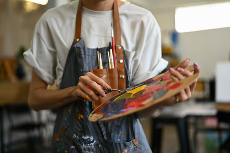 Artist holding palette and brush standing in bright studio. Art, education, creativity and people concept.の写真素材