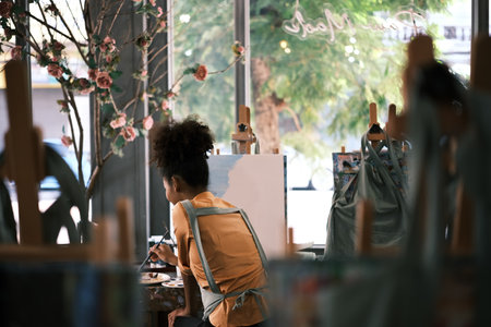 Back view of talented student woman painting on canvas in art classroom. Art, creative learning and...