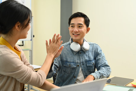 Happy creative man employees give high five, celebrating business success or victory with his...