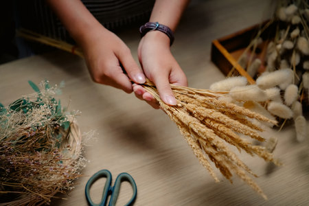Cropped shot of florist making a bouquet of dried flowers at her workstation. Small business concept.の写真素材