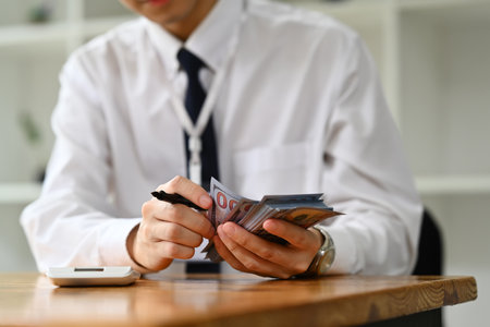 Cropped shot of man bank teller hands counting dollar banknotes. Currency exchange, loan approved finance and banking concept..の写真素材