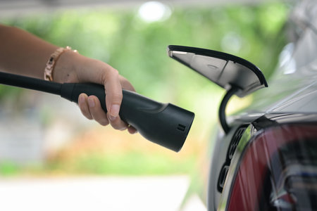 Electric car or ev is charging at station . woman use the wire power cable and plug. zero fuel no transmission.の写真素材