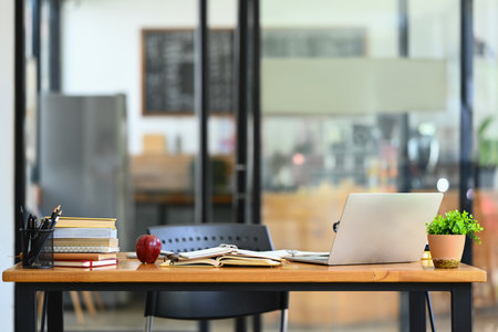 Laptop, books, potted plant and with office supplies on wooden table..の写真素材
