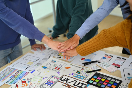 Successful creative business team stacking hands together, celebrating completion of project, motivating and team building.の写真素材