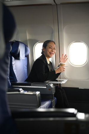 Image of smiling mature businessman in elegant luxury suit sitting in aircraft during business travel.の写真素材