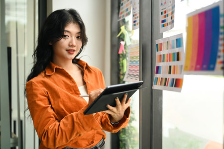 Young creative woman working with color palette, choosing color samples for design project at graphic studio.の写真素材