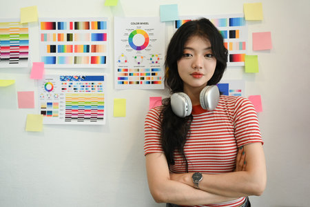 Confident Asian female designer standing with arms crossed and looking at camera. Creative occupation concept.の写真素材