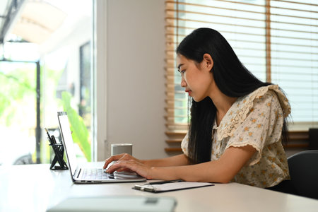Confident young woman in casual clothes typing email, working or shopping online on laptop.の写真素材