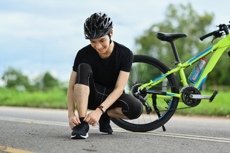 Male cyclist in sports clothes tying shoelaces, getting ready for riding. Active sporty and healthy lifestyle concept.の写真素材