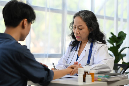 Middle age female doctor taking a female patient pulse at examining room. Medical and health care concept.の写真素材