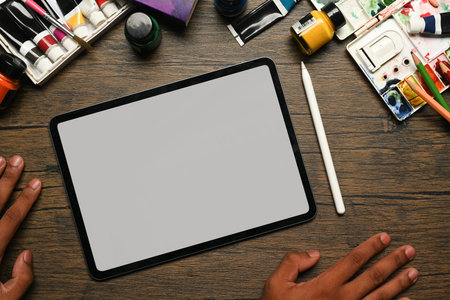 Above view of digital tablet, acrylic paints tubes, pallets and brushes on wooden background.の写真素材