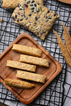 Sliced raw tempeh on wooden plate. Tempeh or Tempe made from fermented soybeans, vegetarian food.
