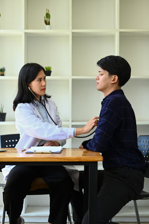 Image of female pediatrician using stethoscope to examine breathing and heartbeat of male patient.の写真素材