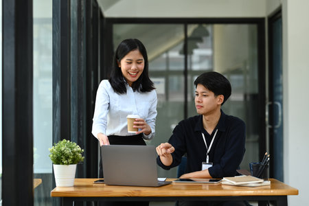 Asian male employee discussing project planning and advising on financial data report with his colleague.の写真素材