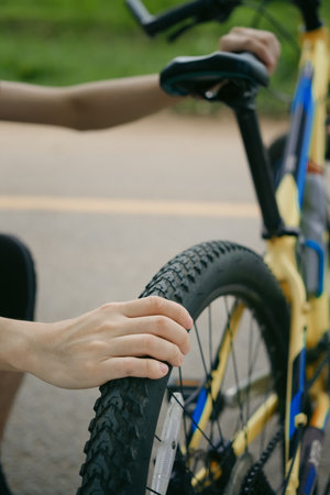 Cropped shot of male cyclist repairing his mountain bike on the road..の写真素材