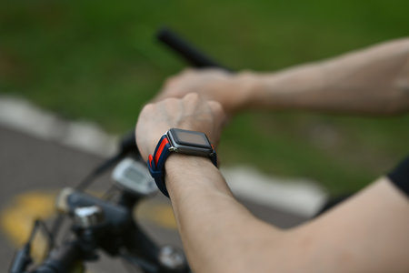 Cropped image of man cyclist sitting on his bicycle and checking sport activity progress data on smartwatch..の写真素材