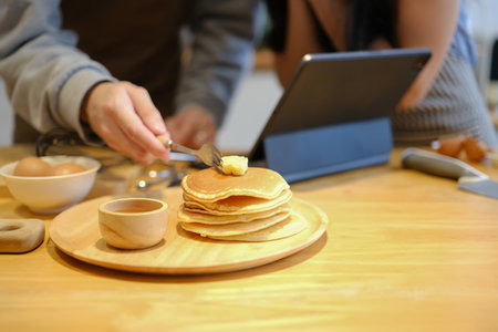 Young man preparing pancakes for breakfast putting butter on the hot pancakes.の写真素材
